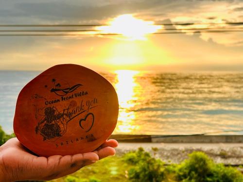 a person holding a beach ball in front of the ocean at Ocean Front Villa in Hikkaduwa