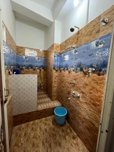 a bathroom with a shower with a blue bucket in it at Solace Suites in Dispur