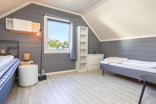 a attic bedroom with a bed and a window at Koselig hus rett ved stranda,nydelig & ferierende! in Grimstad
