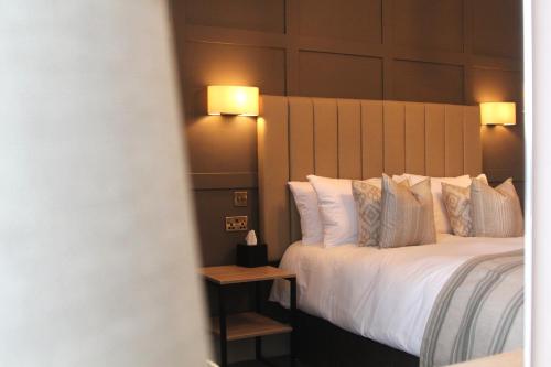a hotel room with a bed with white sheets and pillows at Coach & Horses Dersingham in Dersingham