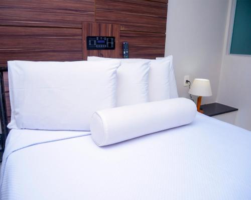 a white bed with white pillows and a clock on the wall at Hotel Sempre Executive in Salvador