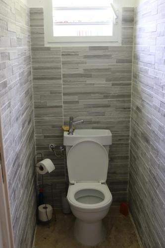a bathroom with a white toilet with a window at Le Chalet des Rêves Ensoleillés in Saint-François