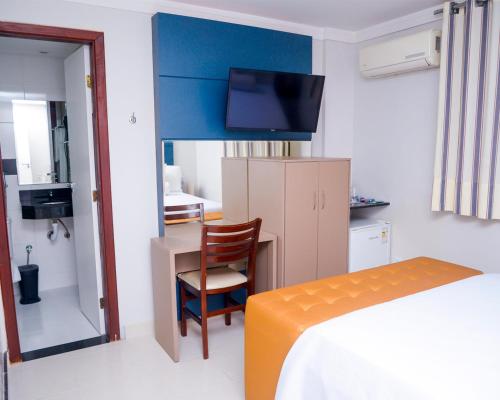 a bedroom with a bed and a desk with a chair at Hotel Sempre Executive in Salvador