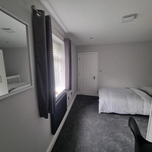 a bedroom with a bed and a window and a mirror at A luxury 2 bed flat in Romford in Romford