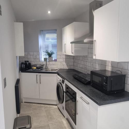 a kitchen with a microwave oven and a sink at A luxury 2 bed flat in Romford in Romford