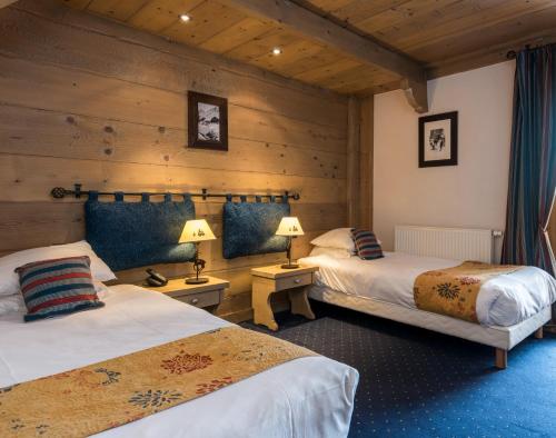 two beds in a room with wooden walls at Chalet Hotel L’Ecrin in Tignes