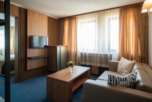 a hotel room with a couch and a tv at Legends Hotel in Sofia