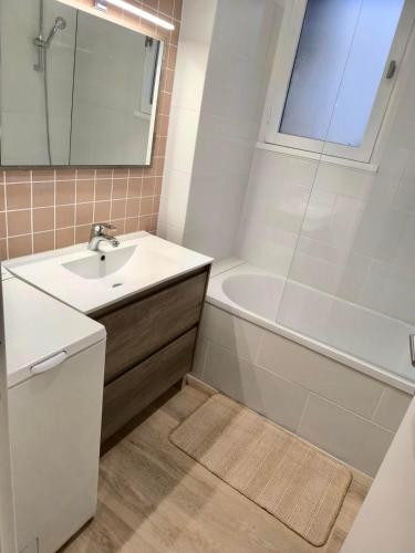 une salle de bain avec un lavabo, une baignoire et un miroir dans l'établissement Le parfum d élégance - Seignosse - Plage, à Seignosse