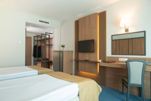 a hotel room with a bed and a desk with a television at Legends Hotel in Sofia