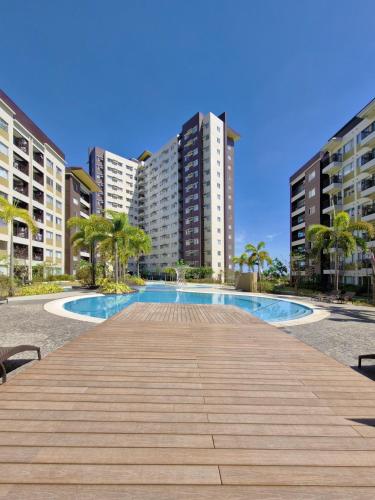 a boardwalk leading to a swimming pool with tall buildings at Avida Towers Atria in Iloilo City