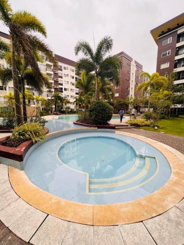 a large swimming pool with palm trees and buildings at Avida Towers Atria in Iloilo City
