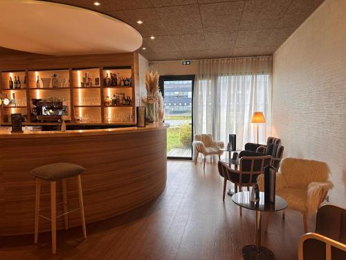 a restaurant with a bar with chairs and tables at Brit Hotel & Spa Saint Brieuc Plérin in Plérin
