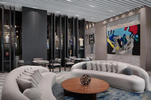 a lobby with two white couches and tables and chairs at Four Points by Sheraton Izmir in Izmir