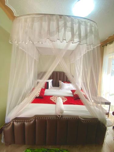 a bedroom with a canopy bed with a red blanket at Jebel Hotel & Lounge Buloba in Kampala