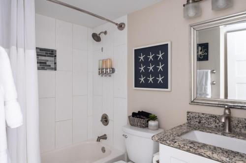 a bathroom with a tub and a toilet and a sink at CDM 304 - Beachfront Serenity in Galveston