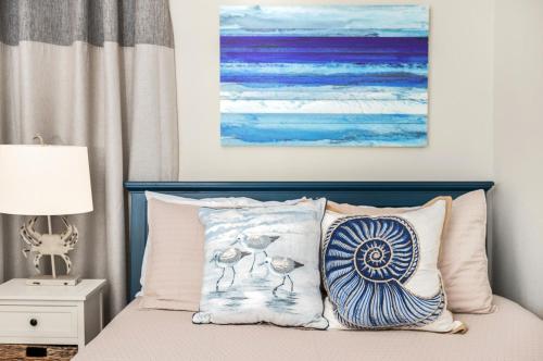 a bedroom with a bed with two pillows and a painting at CDM 304 - Beachfront Serenity in Galveston