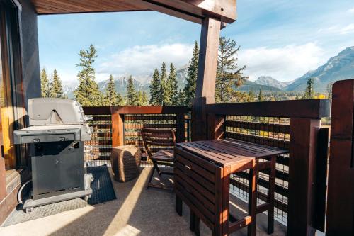 a grill and a table on a balcony with a view at Rundle Cliffs Lodge by Canmore Premier in Canmore