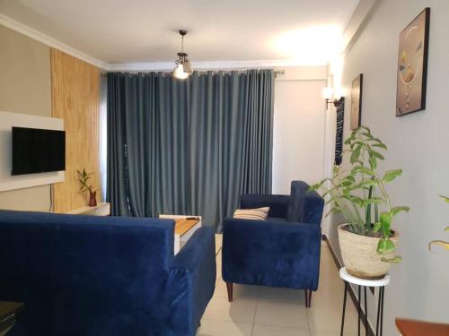 a living room with two blue chairs and a couch at cari haven homes in Buwate