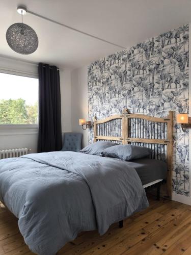 - une chambre avec un grand lit et du papier peint floral dans l'établissement Le Précieux, à Fécamp