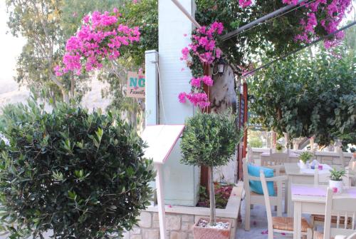 a patio with tables and pink flowers and trees at River Side in Georgioupolis