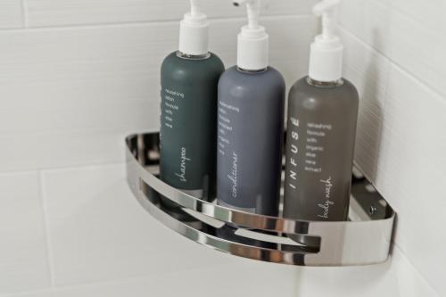 a rack with three shampoo bottles on a wall at Sonesta Essential Vacaville Napa Valley in Vacaville
