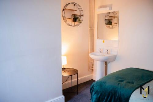 a bathroom with a sink and a bed and a mirror at Spacious 10 Bed Contractor Pad in Bray