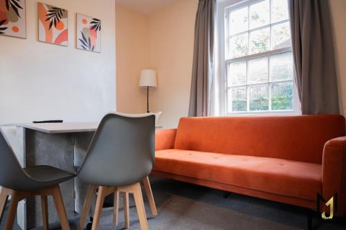 a living room with an orange couch and a desk at Spacious 10 Bed Contractor Pad in Bray