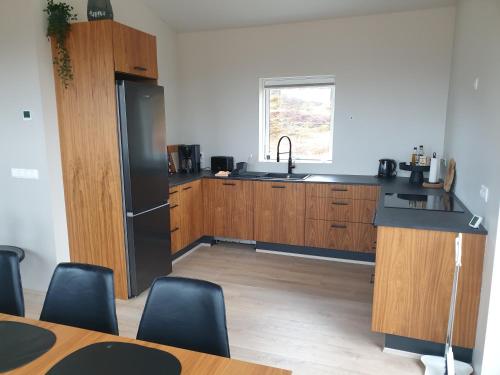 a kitchen with a black refrigerator and wooden cabinets at Hvammur 10 with private hot tub in Kaldrananes