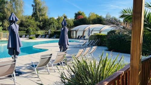 - un groupe de chaises longues et de parasols à côté de la piscine dans l'établissement Les Cottages du Lac, à Parentis-en-Born