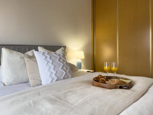a bed with a tray of bread and two glasses of wine at FuensalidaHomes 208 in Fuensalida