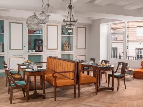 a dining room with tables and chairs and a chandelier at Hotel Madeleine De Senlis in Paris