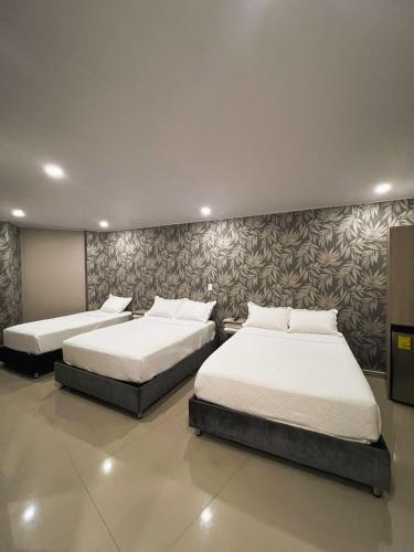 two twin beds in a room with a wall at Oasis Hotel in San Andrés