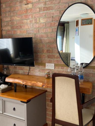 a mirror on a brick wall with a desk and a tv at East Cliff Folkestone Guest Suite With Own Entrance in Folkestone
