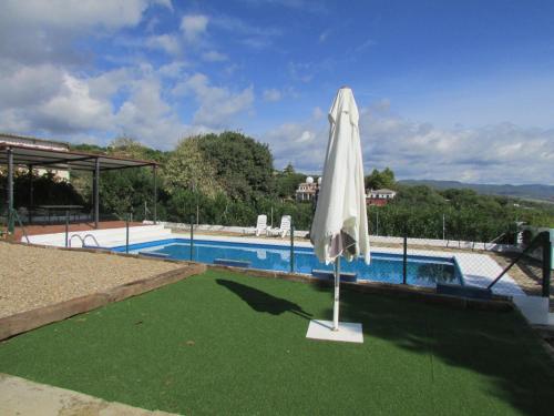 a white umbrella sitting next to a swimming pool at Villa Alare in Almodóvar del Río