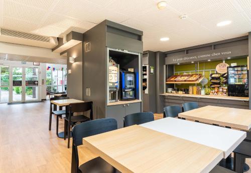 un restaurant avec des tables, des chaises et un comptoir dans l'établissement B&B HOTEL Nantes Atlantis Le Zenith, à Saint-Herblain