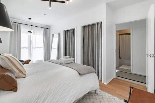 a white bedroom with a large bed and windows at Cute 1Bed Loft at The Foundry - Steps to Riverside in Cleveland