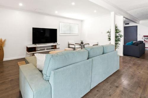 a living room with a blue couch and a flat screen tv at Newly Renovated 6BR 3BA Port Arthur Holiday Home with Hot Tub in Port Arthur