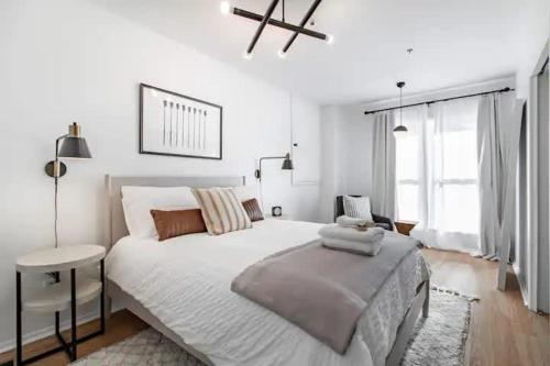 a white bedroom with a large bed and a window at Cute 1Bed Loft at The Foundry - Steps to Riverside in Cleveland