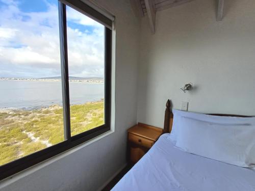 a bedroom with a bed and a large window at Whale Watch Cottage in St. Helena Bay