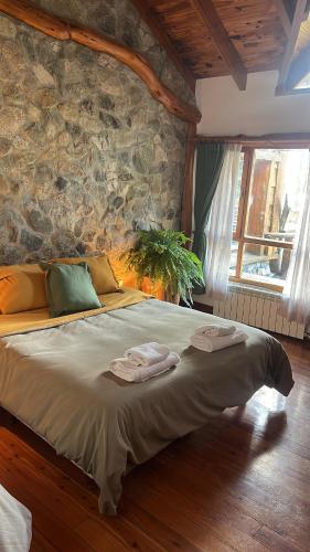 a large bed in a room with a stone wall at Miradas del lago in Epuyén