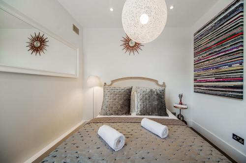 a bedroom with a bed with white pillows and a chandelier at Primrose Boutique Home in London