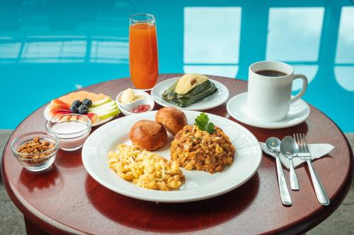 a table with plates of breakfast food and a cup of coffee at Hotel Libertador in Loja