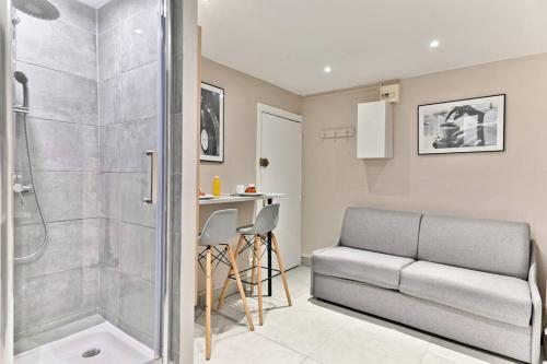 a bathroom with a shower and a couch and a sink at Studio Confortable au cœur du Quartier Sentier in Paris