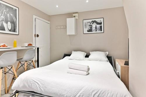 a bedroom with a large white bed and a table at Studio Confortable au cœur du Quartier Sentier in Paris