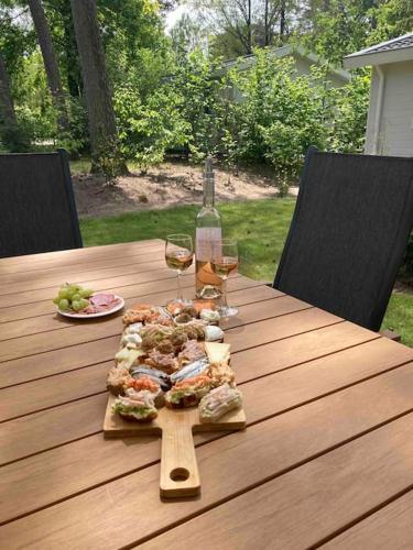 a wooden table with a pizza and two glasses of wine at Chalet de Veluwe Europarcs in Otterlo