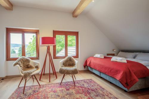 a bedroom with a bed and two chairs and a lamp at Haus am Rebberg in Öhningen