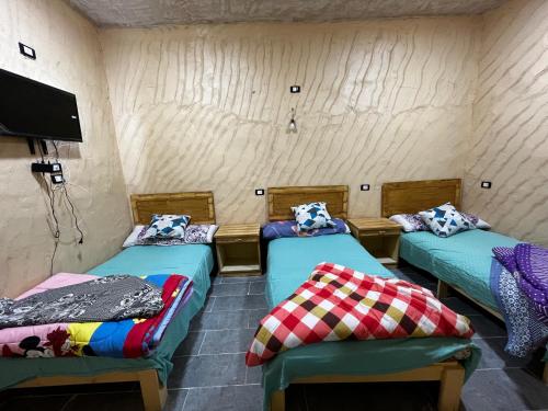 a room with three beds and a flat screen tv at Adrar AbreQ-Bet AlkaRam in Siwa