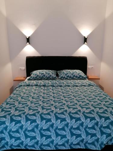 a bedroom with a bed with a blue comforter at Apartman Lamela in Zenica