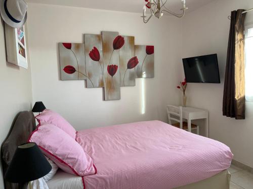1 dormitorio con 1 cama rosa y 4 cuadros en la pared en Les hortensias, en Les Sables-dʼOlonne