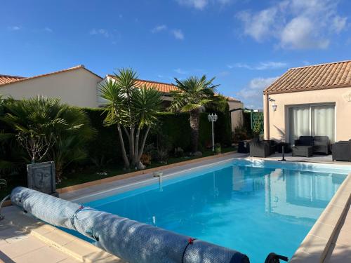 una piscina con palmeras y una casa en Les hortensias, en Les Sables-dʼOlonne